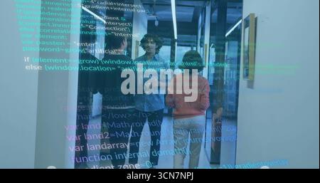 Reviewing code, three developers gathering in office hallway with digital display, glass partitions Stock Photo