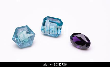 Three different colored gems are shown on a white background. The blue gem is the largest and is in the middle. The purple gem is smaller and is on th Stock Photo