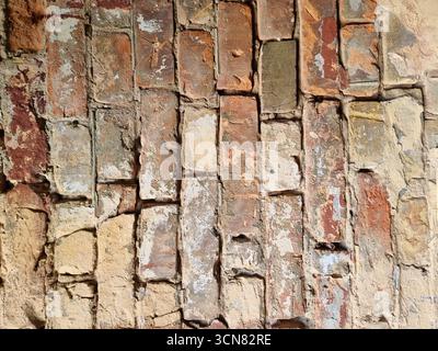 Vintage brick wall built from red and yellow Kyiv bricks in portrait orientation. Strong contrast lighting highlights the aged texture, creating an au Stock Photo