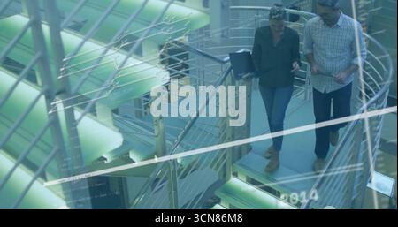 Descending staircase professionals consulting laptop and tablet in office atrium, copy space Stock Photo