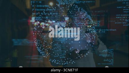 Holding smartphone, European man wearing sweater standing on street at night, with code overlay Stock Photo