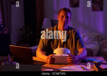 Portrait of Man Sitting at Desk Holding Virtual Reality Headset Stock Photo