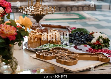 Beautifully arranged Ukrainian Easter celebration display with ornate kulich bread, vibrant floral bouquet, black grapes, and intricately patterned pa Stock Photo