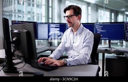 Elderly Engineer Developing Cyber Security Program On Desktop Computer Screen Stock Photo