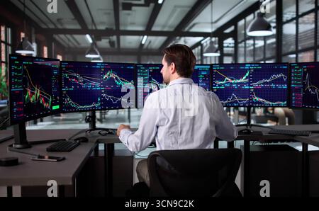 Senior Broker Analyzing Stock Market Data At Office Desk With Screens. Stock Photo
