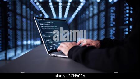 Man In Dark Hoodie Hacks Into Online Server For Cyberattack. Stock Photo