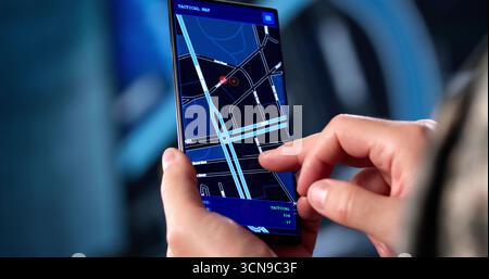Soldier In Camouflage Uniform Navigates Military Position Using GPS Map. Stock Photo
