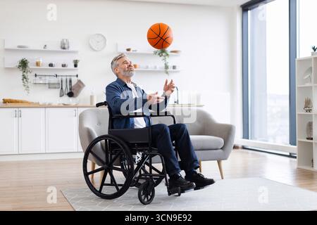 Man in wheelchair practicing basketball in modern living room Stock Photo