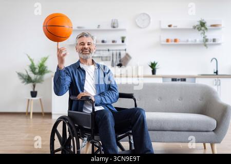 Disabled man practicing basketball skills while in wheelchair indoors Stock Photo