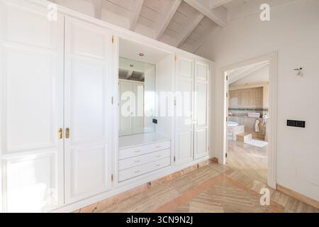 an image of a large white fitted wardrobes next to private bathroom in master bedroom Stock Photo