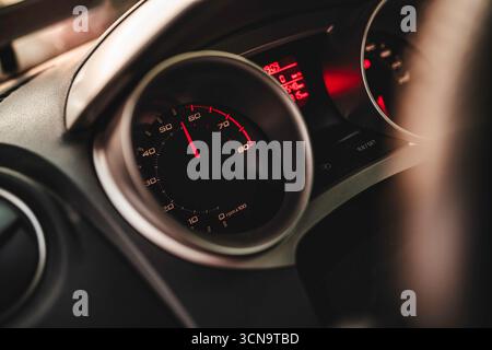 Car dashboard displaying a tachometer with a red needle indicating engine revolutions per minute, symbolizing speed, performance, and modern vehicle t Stock Photo