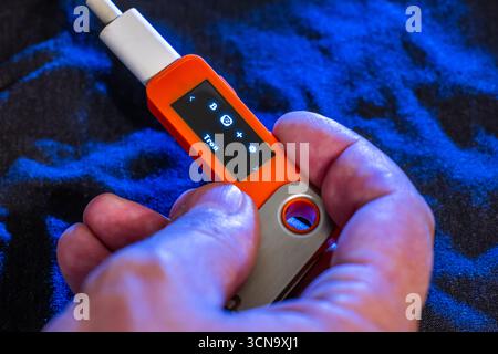 Hand holding orange hardware wallet with Tron symbol on its screen. Stock Photo