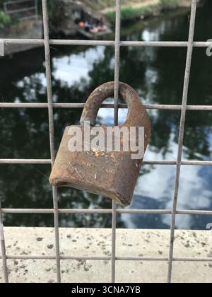 rusty old padlock on wire fence on soft focus background Stock Photo
