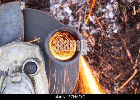 A detailed closeup of a grinding wheel cutting a metal pipe, emitting bright sparks. Depicts the intensity and energy of industrial and metalworking p Stock Photo