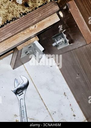 Cairo, Egypt, September 4 2025: maintenance of a bed frame, with a wrench on the floor, the metal frame components of a wooden bed, hinges and a locki Stock Photo