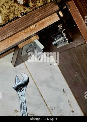 Cairo, Egypt, September 4 2025: maintenance of a bed frame, with a wrench on the floor, the metal frame components of a wooden bed, hinges and a locki Stock Photo