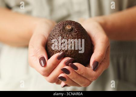 Woman holding avocado fruit. Closeup of hands with fresh organic food. Healthy lifestyle and nutrition concept. Natural tropical fruit in focus. Stock Photo