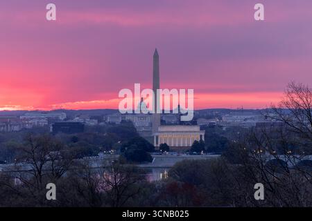 Sunrise over Washington, D.C. with the Lincoln Memorial, Washington Monument, and U.S. Capitol silhouetted against a vibrant pink and purple sky. Stock Photo