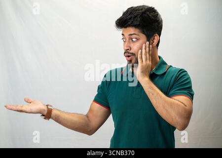 A young man with a surprised expression and a hand to his chin. Stock Photo