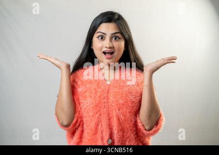 A young woman with a shocked expression and hands raised. Stock Photo