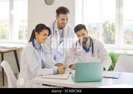 Three doctors are gathered around laptop, engaged in collaborative effort to enhance patient care.  Stock Photo