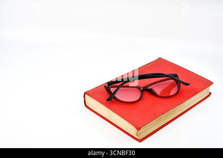 Pair of women's reading glasses on the cover of a book isolated on a plain white background. Copy space. Stock Photo