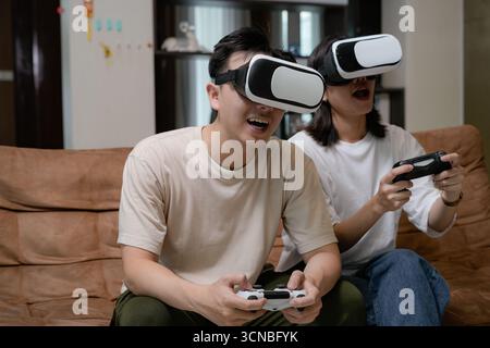 couples relax at home, immersed in a virtual reality game Stock Photo