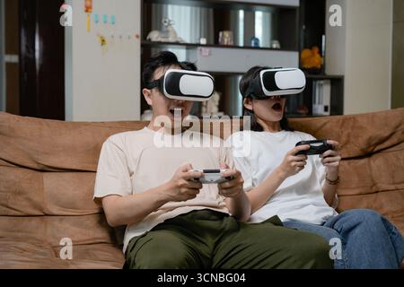 couples relax at home, immersed in a virtual reality game Stock Photo