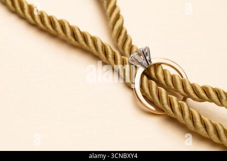 Gold Engagement Diamond Ring and Rope Knot Background Stock Photo