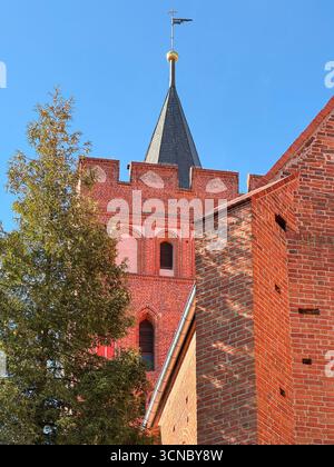 Detailed side view of catholic brick church built in 1370 in Europe, showing roof spire, tower, and decorative brick elements. Stock Photo