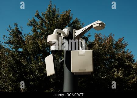 Modern surveillance cameras on a pole in Belgrade against blue sky and trees. Stock Photo