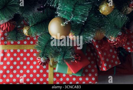 Close-up of Christmas gifts and ornaments under a decorated tree, showing festive colors, textures and holiday mood for seasonal designs Stock Photo