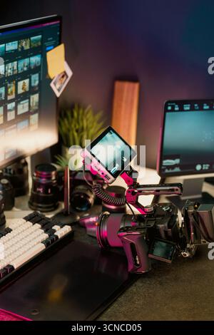Professional video camera editing setup studio workspace with camera gear, computer screens displaying footage thumbnails, and digital production tool Stock Photo