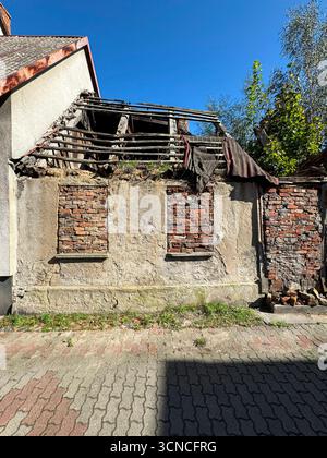 Old decaying building with partially collapsed roof and weathered brick walls. The structure reflects abandonment and urban decay, offering texture an Stock Photo