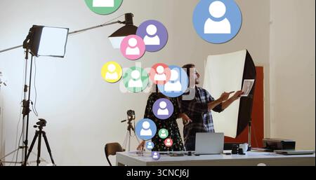 Pointing creators casual attire reviewing prints in studio with floating user icons, copy space Stock Photo