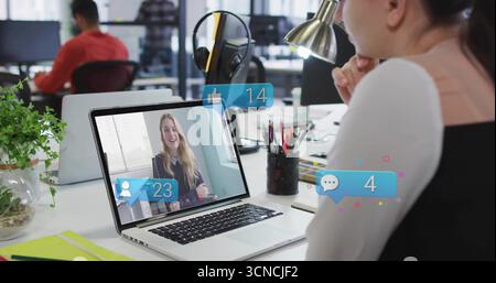 Office worker focusing on laptop call with floating notifications at desk with lamp, copy space Stock Photo
