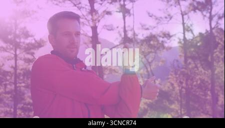 Stretching hiker pulling arm across chest in forest clearing, with red jacket, watch, copy space Stock Photo