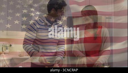 Couple chopping vegetables with knives on cutting boards in home kitchen, with US flag overlay Stock Photo