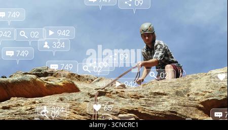 Scaling climber wearing helmet harness rope on sandstone face with floating icons, copy space Stock Photo