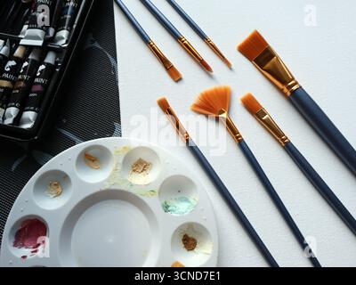 A vibrant studio scene featuring a round color palette, assorted paints and several brushes laid out for painting, blending colors, and creative Stock Photo