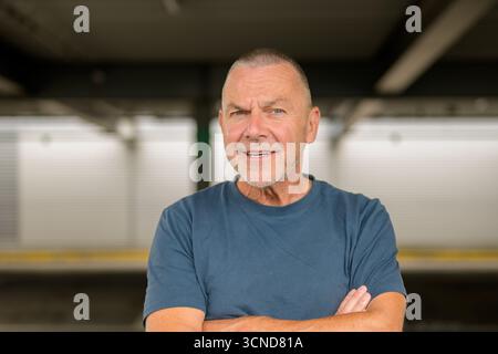 Cheerful senior man with crossed arms smiling confidently in a casual pose. Stock Photo