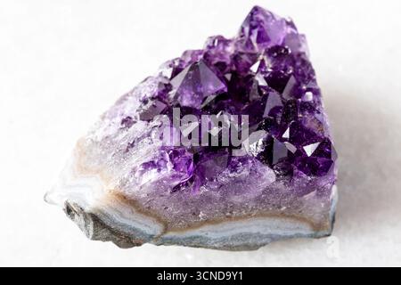 sample of cut geode of amethyst mineral crystals on white marble background close up from Russia Stock Photo