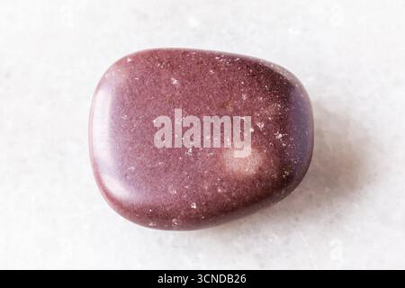 sample of polished red brown quartzite rock on white marble background close up from Karelia, Russia Stock Photo