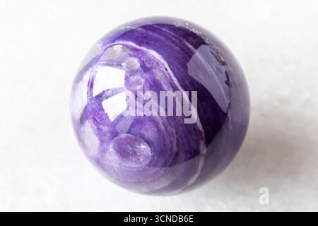 polished ball from charoite mineral on white marble background close up from Russia Stock Photo
