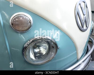 Close-up of a vintage two-tone blue and white Volkswagen van front with classic headlights and iconic VW emblem Stock Photo