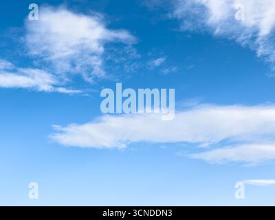 Clear blue sky with high scattered white cumulus clouds on a sunny day. copyspace Stock Photo