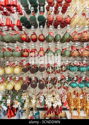 A store display with a variety of colourful hanging Christmas glass ornaments and baubles in various shapes and sizes arranged on a pegboard wall Stock Photo