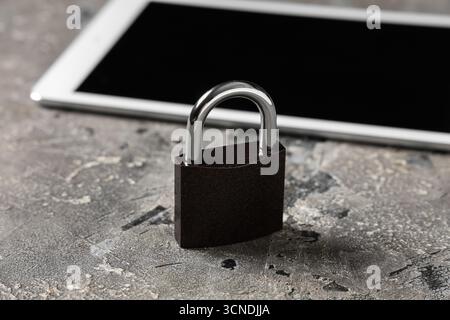 Padlock with tablet computer on grunge background, closeup. Cyber security concept Stock Photo