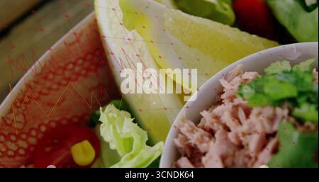 Displaying shredded tuna and lettuce in bowl on table, with herbs, cherry tomatoes, corn kernels Stock Photo