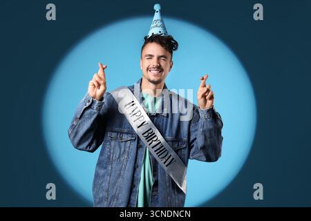 Happy young man making Birthday wish on blue background Stock Photo